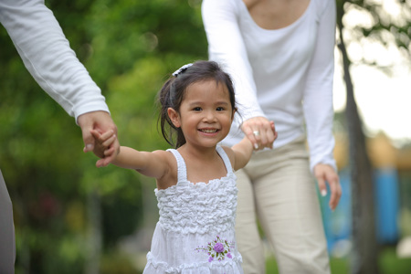 Two parents holding both of their daughters hands.