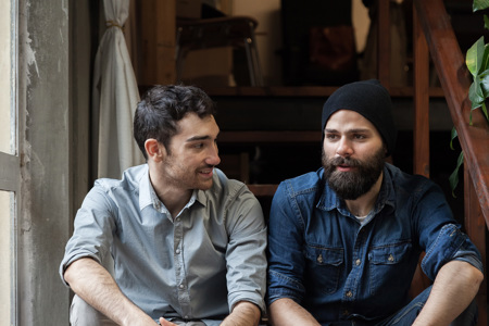 Two young men sitting on a step and having a conversation