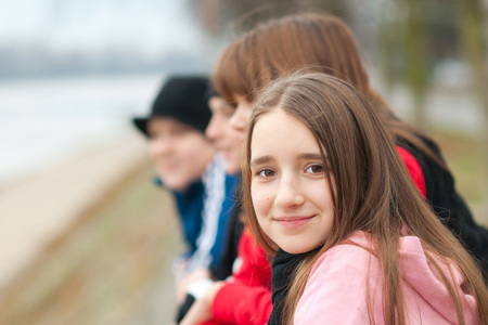 A group of young teenagers standing next to each other outside.