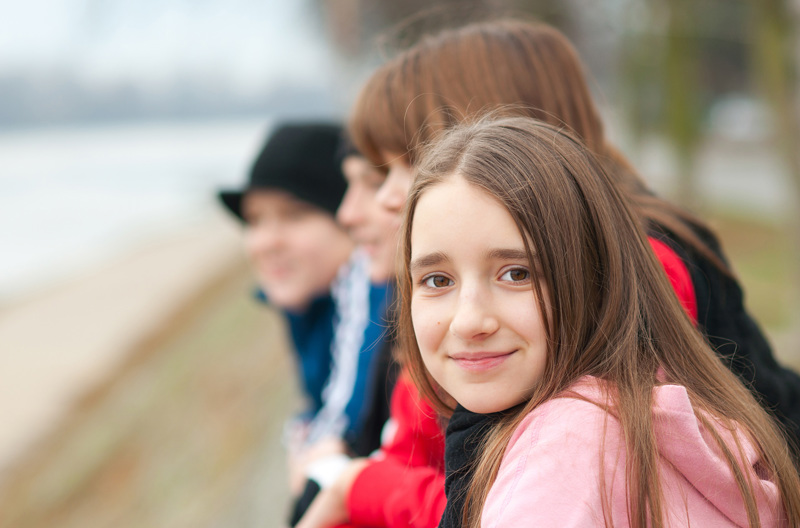 A group of young teenagers standing next to each other outside.