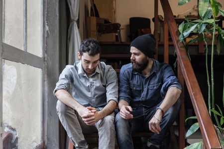 Two friends sitting together on a set of stairs talking.