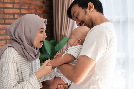Two parents holding their child smiling at each other.