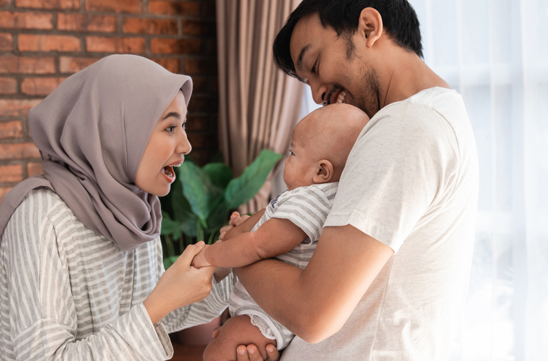 Two parents holding their child smiling at each other. 