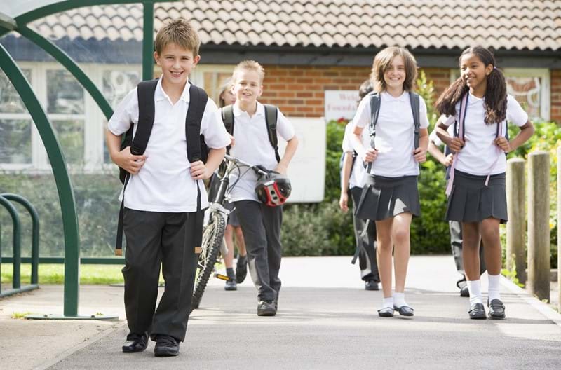 A group of young children wearing white shirts as they walk together to school.