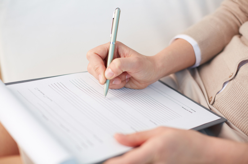 Someone filling out a form on a clipboard.