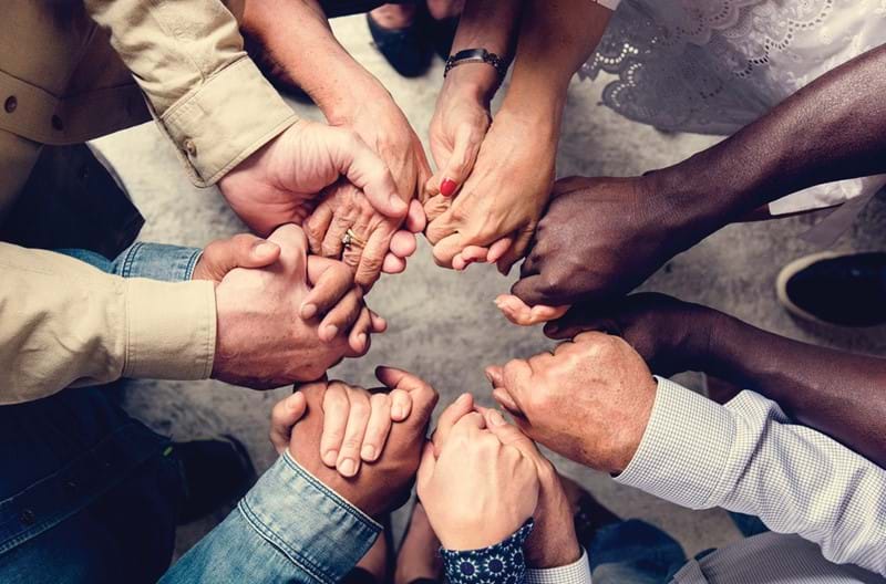 A group of people holding each other's hands in a circle.