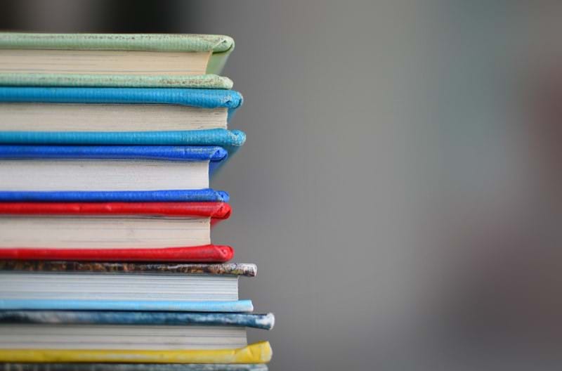 A stack of books with bright red, blue, green, and yellow covers.