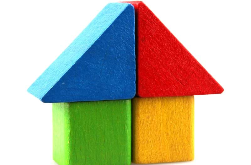 A house built with blue, red, green, and yellow wooden blocks.