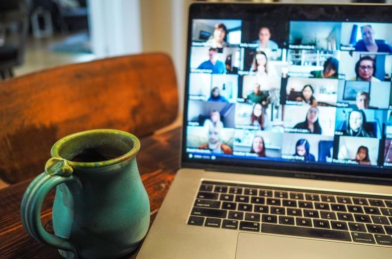 A mug sitting next to an open laptop with a group video call running.