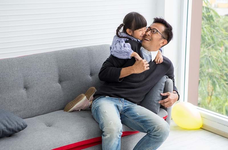 A parent sitting with his child on a couch. 