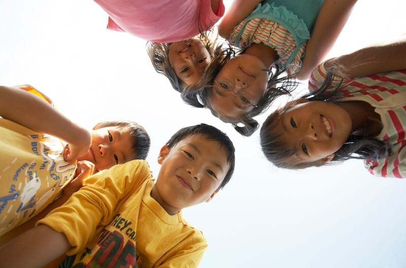 Five children gathering around a camera smiling.