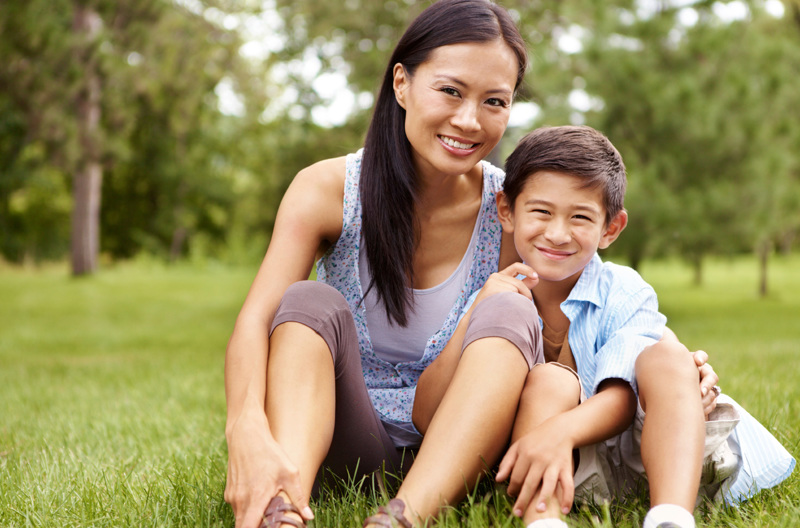 A parent sitting in the grass with their child.