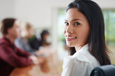 A woman sitting in a chair looking back and smiling.