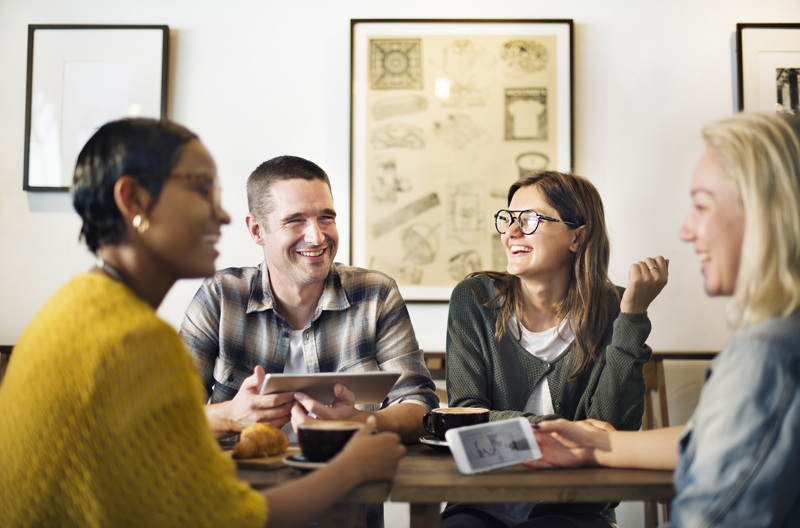 A group of friends sitting together at a table eating and talking.