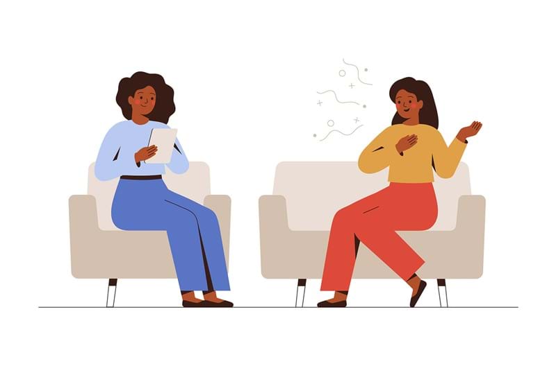 An illustration of a counsellor sitting on a couch listening to a woman talking sitting on another couch. 