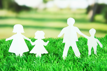 A paper family design stuck in grass.