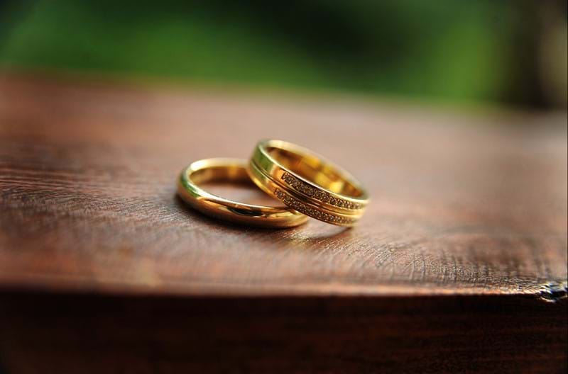 Two wedding bands stacked together on a wooden surface.