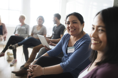 A group of people sitting together in a circle smiling.